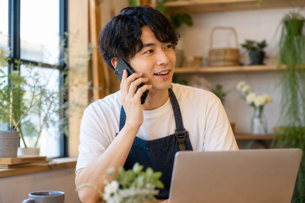スマホで電話をする個人事業主の男性